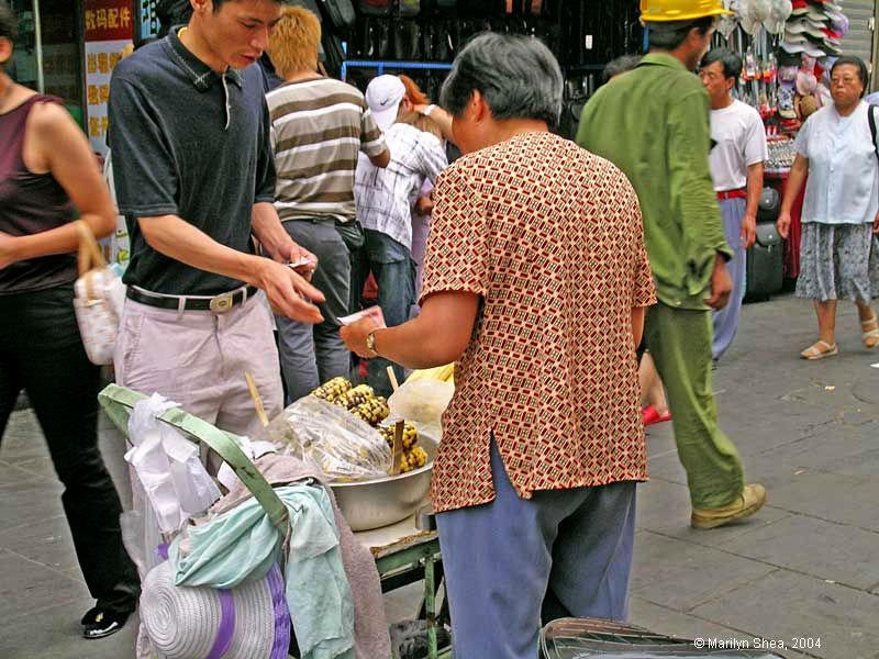 a young man buys an ear of corn from the vendor