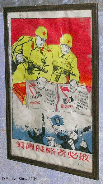 Poster shows two PLA soldiers behind a stack of Little Red Books holding machine guns pointed at small people below waving a flag with a dollar sign on it