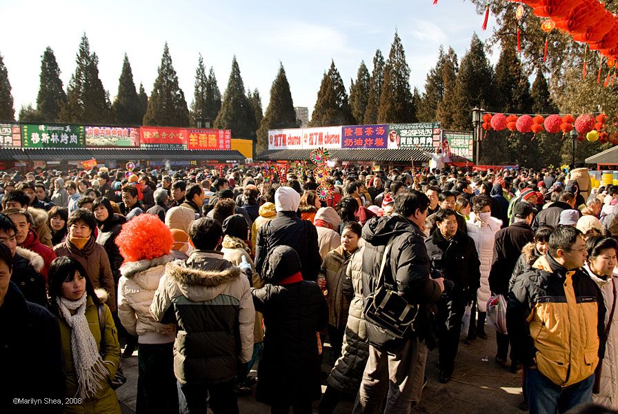 Crowd of people in a square - vendors booths in distance