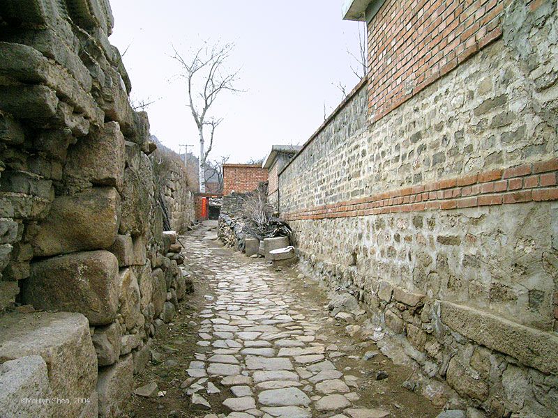 Alley of the old village with brick repairs on the stone walls